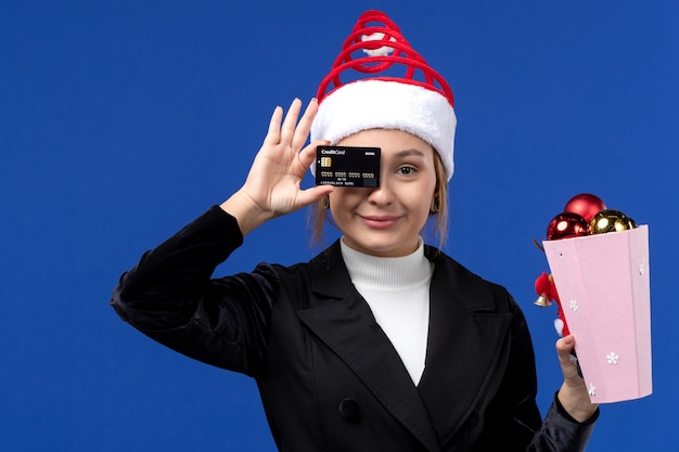 Foto grátis jovem, vista frontal, com brinquedos de árvore e cartão do banco na parede azul do feriado de emoção de ano novo