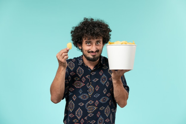 Jovem, vista frontal, segurando uma cesta com batatas cips na parede azul cinema filmes cinema teatro masculino