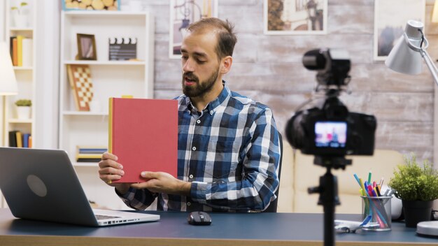 Jovem vlogger famoso gravando uma resenha de um livro para assinantes. Estilo de vida vlogger.