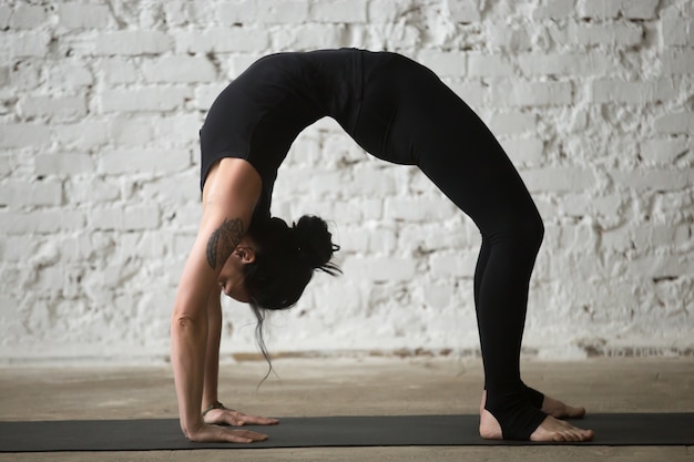 Jovem yogi atraente em urdhva dhanurasana pose, loft bac