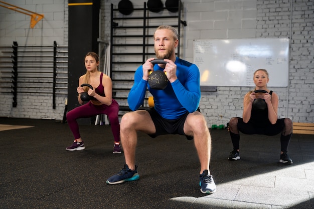 Jovens adultos no ginásio de esporte usando kettlebells