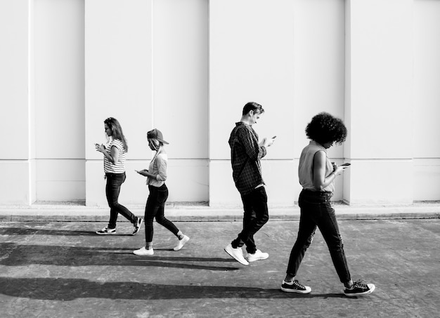 Foto grátis jovens adultos usando smartphones enquanto caminham ao ar livre