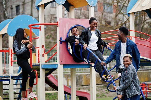 Jovens amigos africanos da geração do milênio no playground deslizam e balançam Pessoas negras felizes se divertindo juntos Conceito de amizade da geração Z