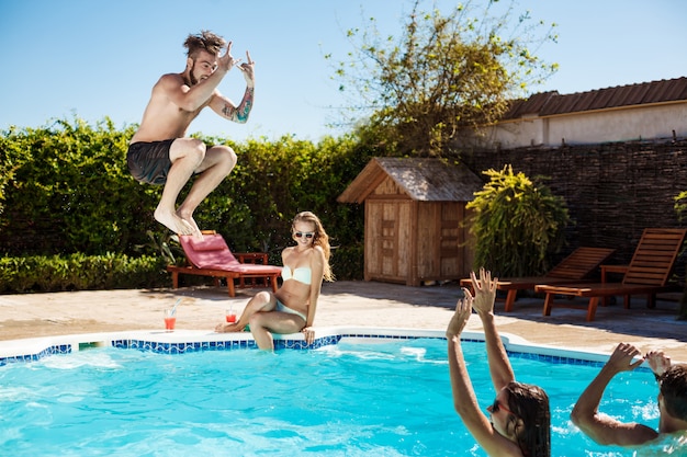 Jovens amigos alegres sorrindo, rindo, relaxando, nadando na piscina