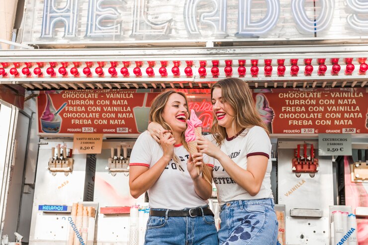 Foto grátis jovens amigos comendo sorvete no parque de diversões