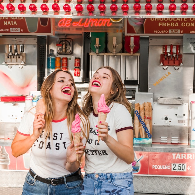 Jovens amigos comendo sorvete no parque de diversões
