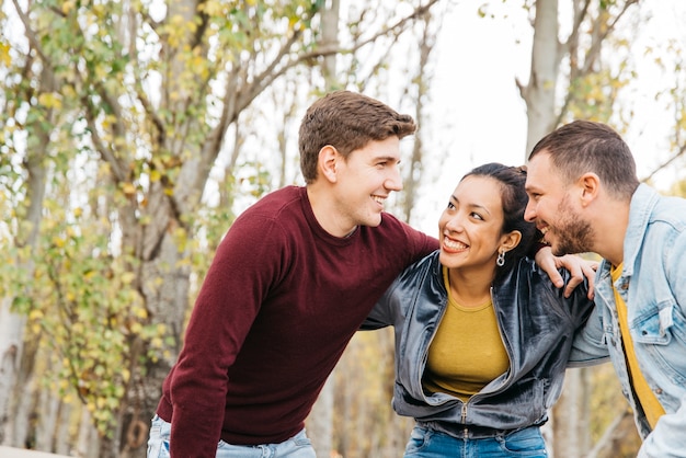 Jovens amigos multirraciais em pé com as mãos nos ombros