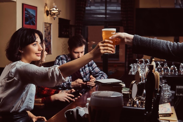 Foto grátis jovens amigos multirraciais no bar. barman dando copo de cerveja ao cliente no pub.