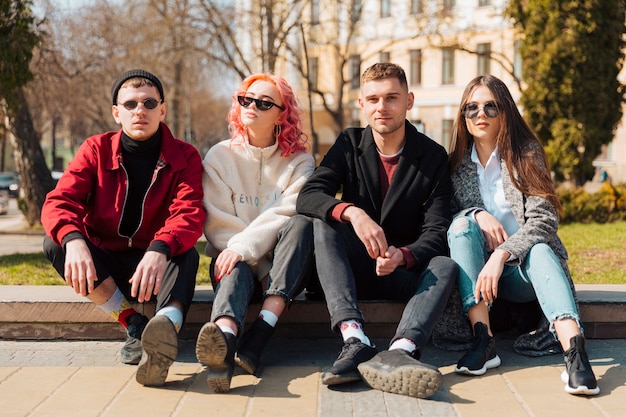 Foto grátis jovens amigos sentados na calçada na cidade