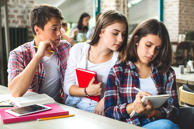 Foto grátis jovens assistindo menina escrevendo no caderno