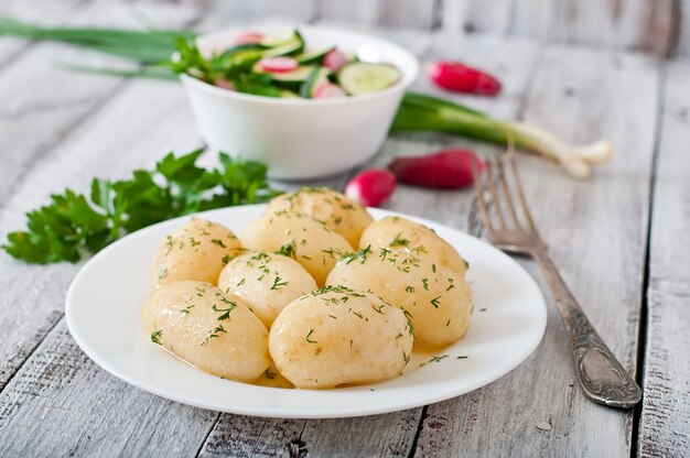 Jovens batatas cozidas com manteiga e endro em um prato branco