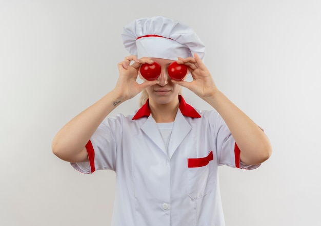 Jovens bonitas cozinheiras com uniforme de chef colocando tomates nos olhos