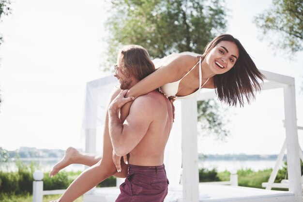 Jovens bonitos gostam disso. Um homem segura uma mulher nos ombros, eles são brincalhões e românticos.