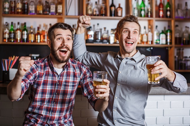 Foto grátis jovens com cerveja assistindo futebol em um bar