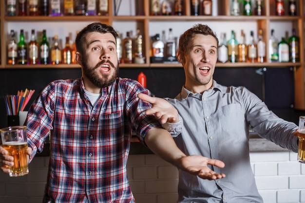 Jovens com cerveja assistindo futebol em um bar