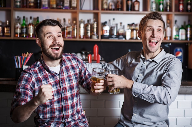 Foto grátis jovens com cerveja assistindo futebol em um bar