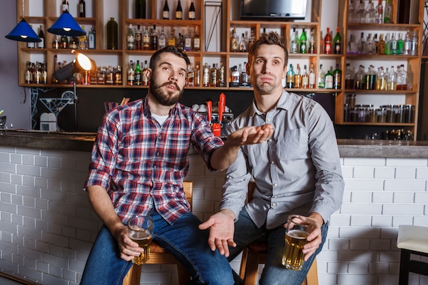 Jovens com cerveja assistindo futebol em um bar