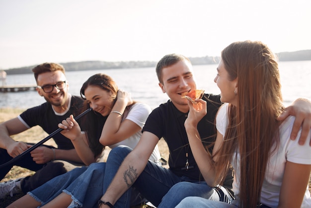 Jovens comendo pizza e fumando shisha na praia