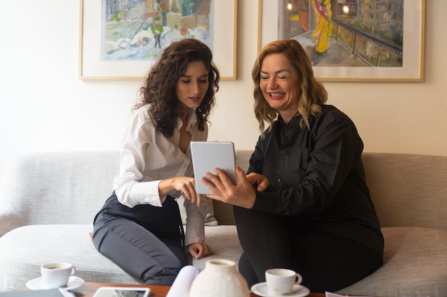 Jovens e mulheres de meia idade usando tablet juntos
