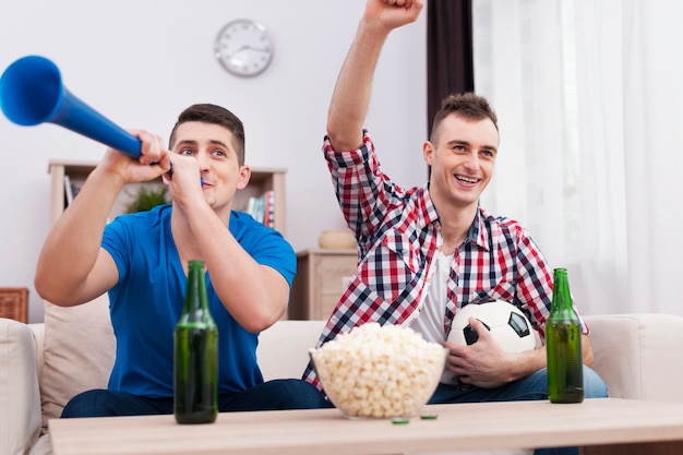 Foto grátis jovens em êxtase torcendo pelo futebol em casa