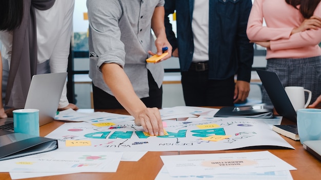 Jovens empresários e empresárias asiáticos felizes, reunindo-se com ideias sobre um novo projeto de papelada