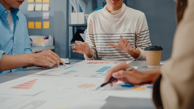 Jovens empresários e empresários asiáticos felizes se reunindo com ideias novas sobre o projeto