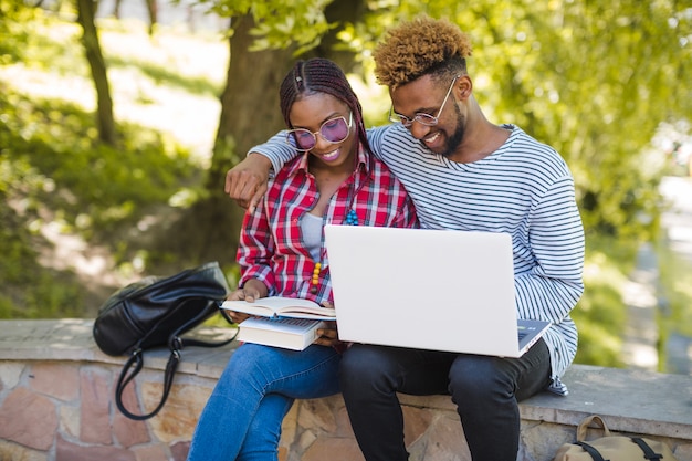 Jovens estudantes abraçando estudando no parque