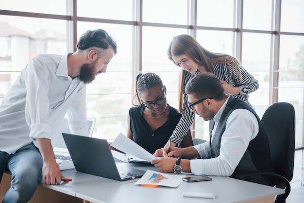 Jovens funcionários sentados no escritório à mesa e usando um laptop