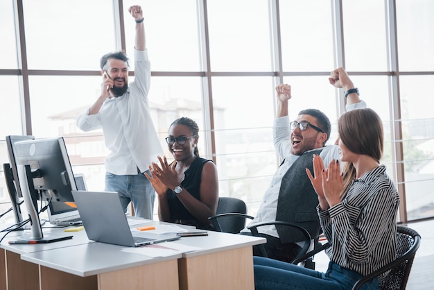 Jovens funcionários sentados no escritório à mesa e usando um laptop