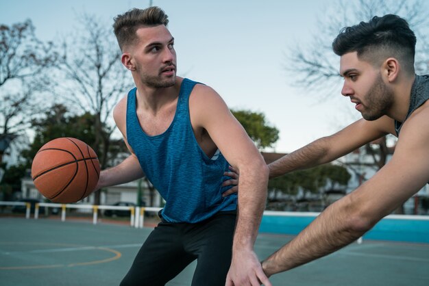 Jovens jogadores de basquete jogando um contra um.