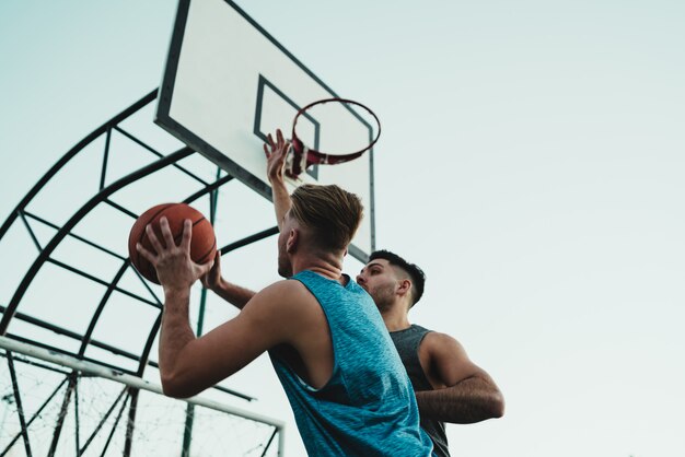 Jovens jogadores de basquete jogando um contra um.