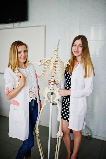 Jovens médicos se divertindo posando com esqueleto