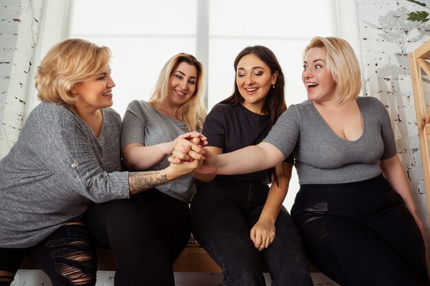 Jovens mulheres brancas com roupas casuais, se divertindo juntos. Amigos sentados perto da janela e rindo, passando um tempo juntos. Bodypositive, nutrição, feminismo, amar a si mesmo, conceito de beleza.