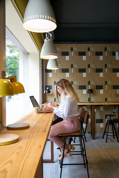 Jovens mulheres brancas trabalhando em laptops e bebendo café