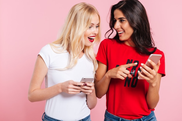 Jovens mulheres loiras e morenas bonitas com smartphones falando isolado