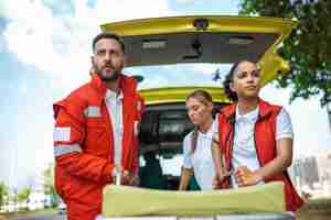 Foto grátis jovens paramédicos movendo maca de ambulância do carro com pressa paramédicos de uniforme tirando maca do carro da ambulância