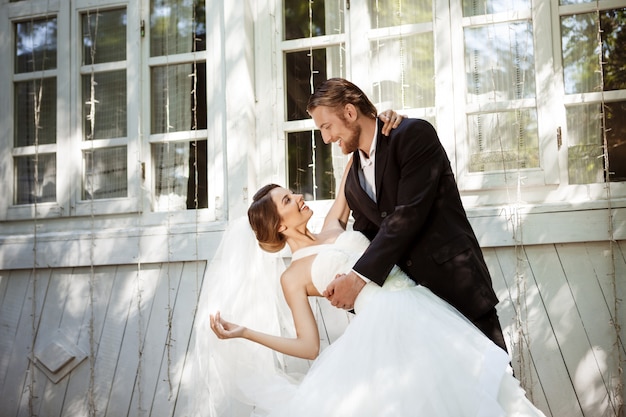 Foto grátis jovens recém-casados elegantes bonitos sorrindo, dançando ao ar livre.