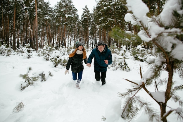 Jovens se divertindo na floresta em clima de inverno nevado.