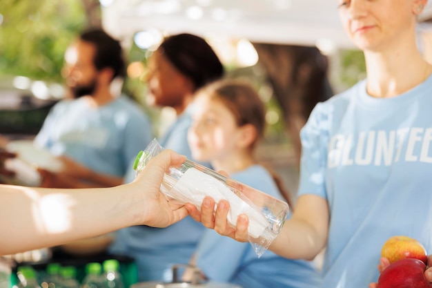 Foto grátis jovens voluntários distribuem compassivamente caixas de alimentos prestando assistência aos pobres imagem detalhada de uma trabalhadora de caridade dando água e frutas frescas aos necessitados menos afortunados