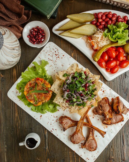 Kabab de carne servido com salada de mangal, cebola, verduras e picles