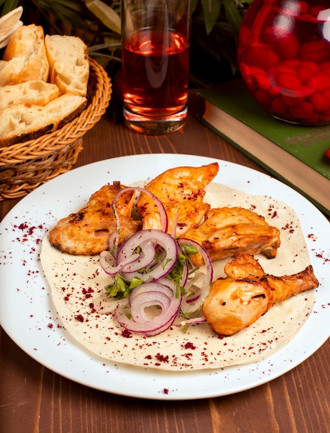 Kebab de asas de frango grelhado servido com composto, salada de legumes de cebola e ervas em chapa branca