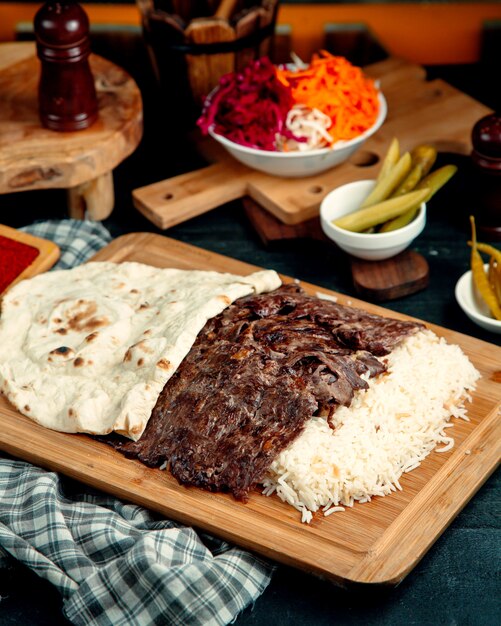 Kebab de carne servido com arroz e pão sírio colocado na tábua de servir de madeira