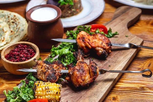 Kebab de frango de vista lateral com verdes tomate cebola vermelha bérberis secas e iogurte em cima da mesa