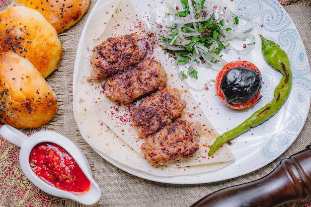 Kebab de lula de vista superior no pão pita com legumes e ervas com cebolas