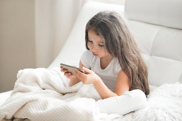 Kid girl jogando jogos no tablet em casa