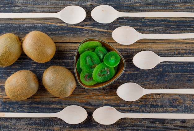 Kiwi com colheres, fatias secas estendidas sobre um fundo de madeira