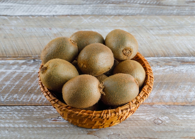 Kiwi em uma cesta de vime em uma mesa de madeira. vista de alto ângulo.