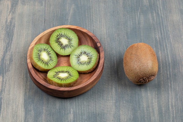 Foto grátis kiwi fatiado com kiwi inteiro em uma mesa de madeira