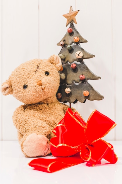 Laço de fita vermelha com ursinho de pelúcia e árvore de Natal