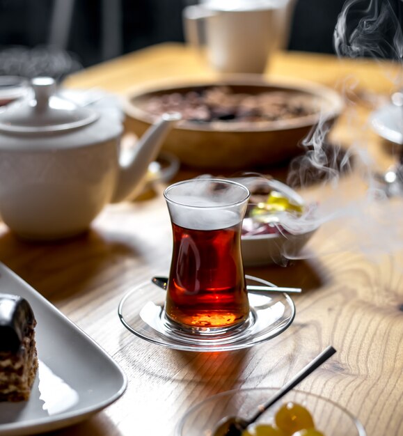 Lado do chá quente com um vapor no copo armudu em uma mesa de madeira